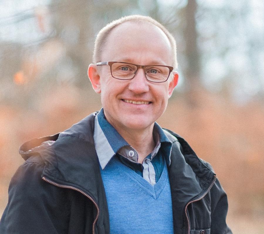 Ein Mann mit Brille und freundlichem Lächeln im Freien