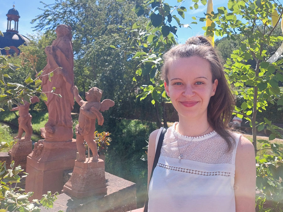 Eine junge Frau in weißem Kleid steht neben Statuen